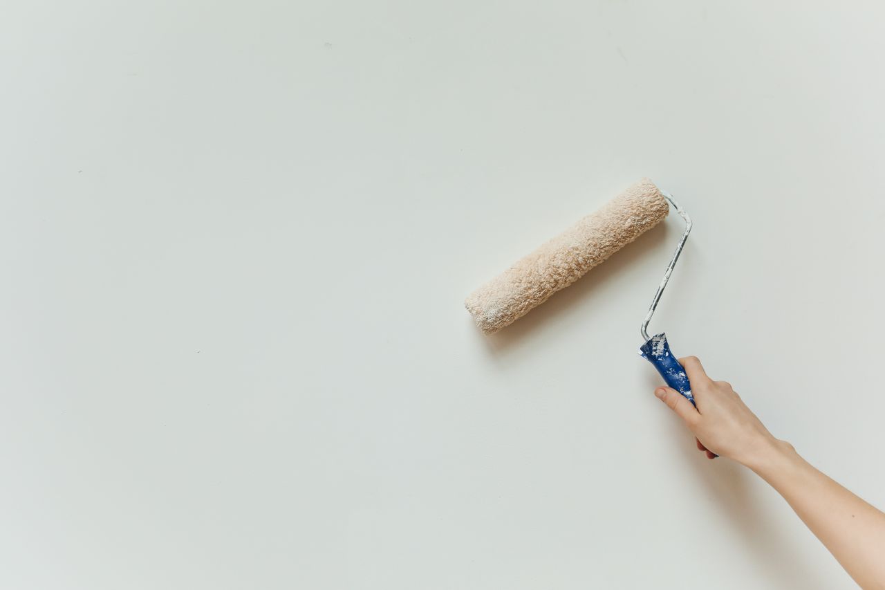The Art of Drawing Readers In: Your attractive post title goes here Close-up of a hand painting a wall with a roller brush during renovation.