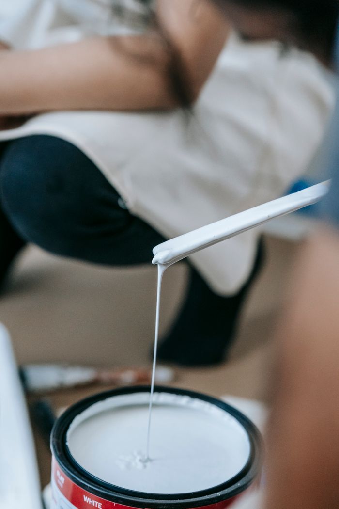 About Close-up of a woman mixing white paint, ready to apply in a home renovation project.
